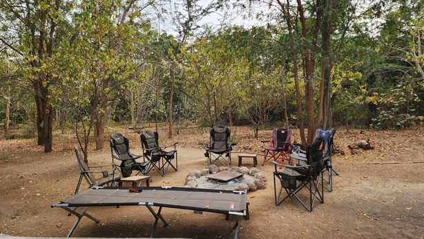 An outdoor camping area with a table and chairs arranged around a central fire pit. - Suñu Tool Private Farm Guesthouse, ferme agroécologique, entourée de nature. (Thiès)