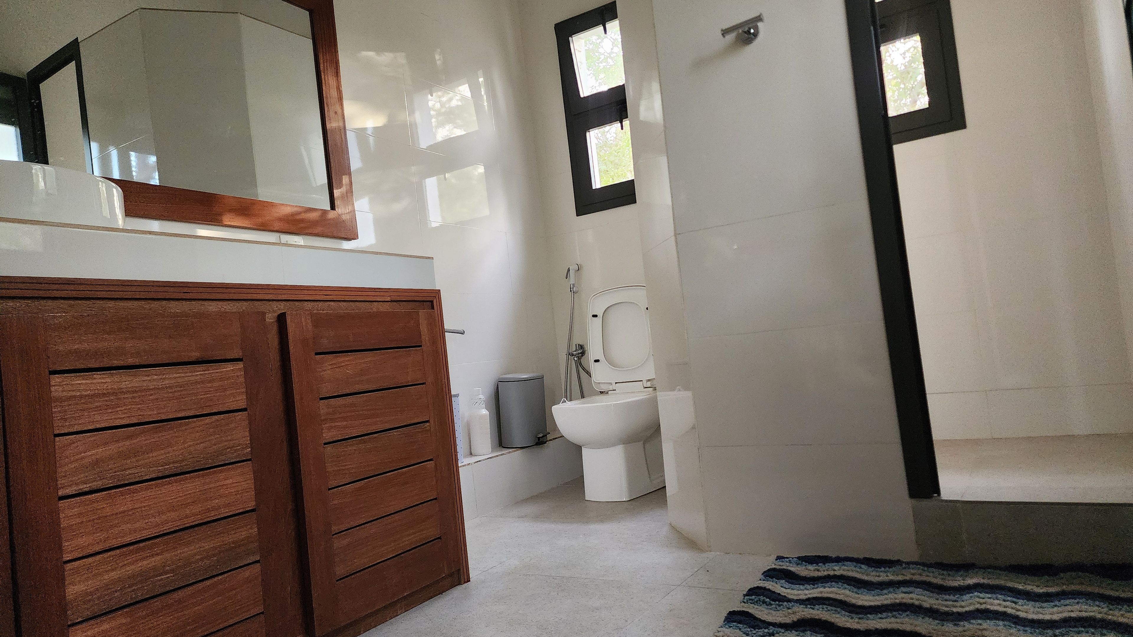 Un baño con tocador de madera, inodoro, bidé y zona de ducha.