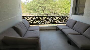 Un balcone con due divani rivolti a una ringhiera decorativa e una vista su alberi.