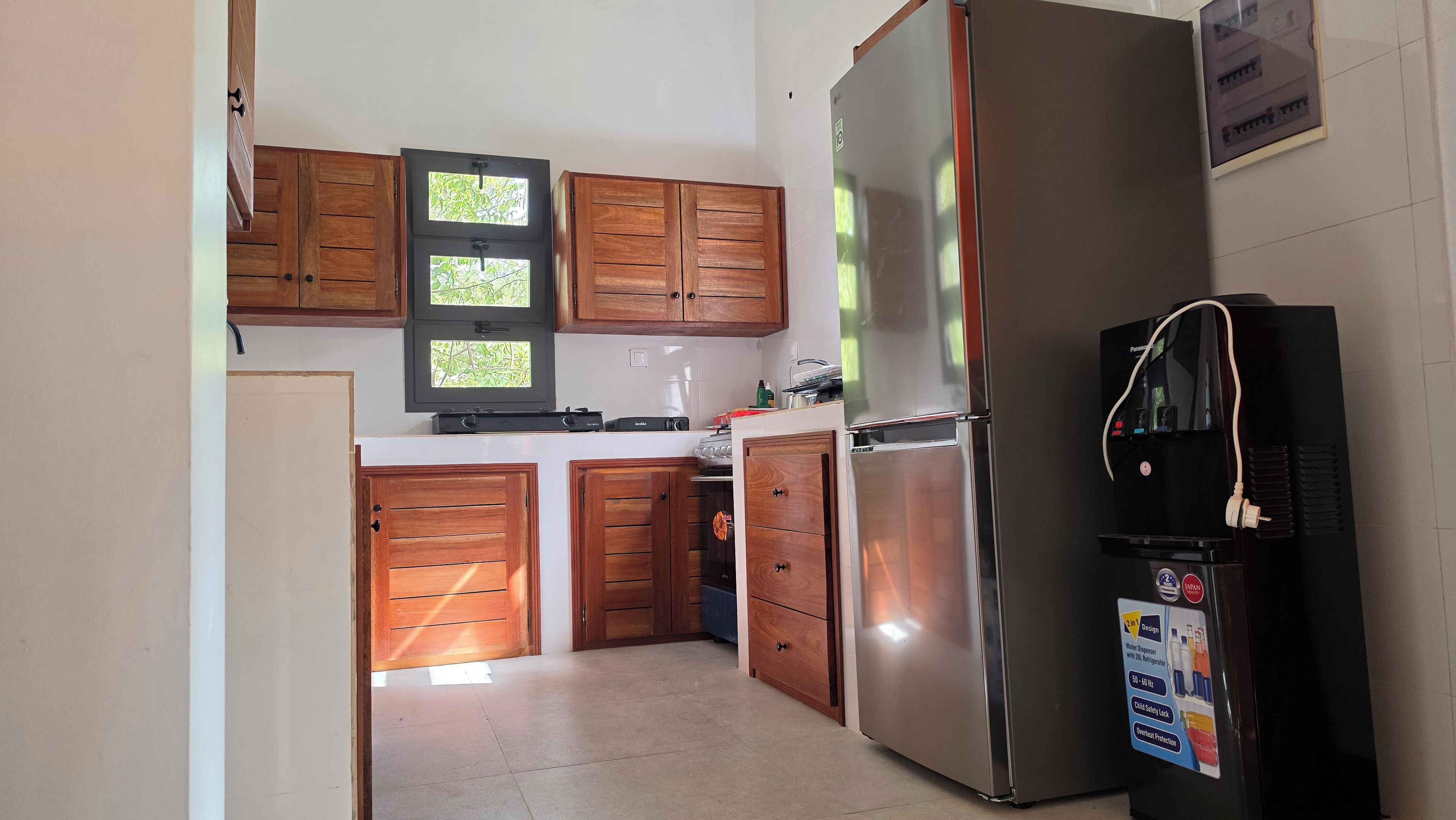 Cocina con armarios de madera, refrigerador de acero inoxidable y dispensador de agua.