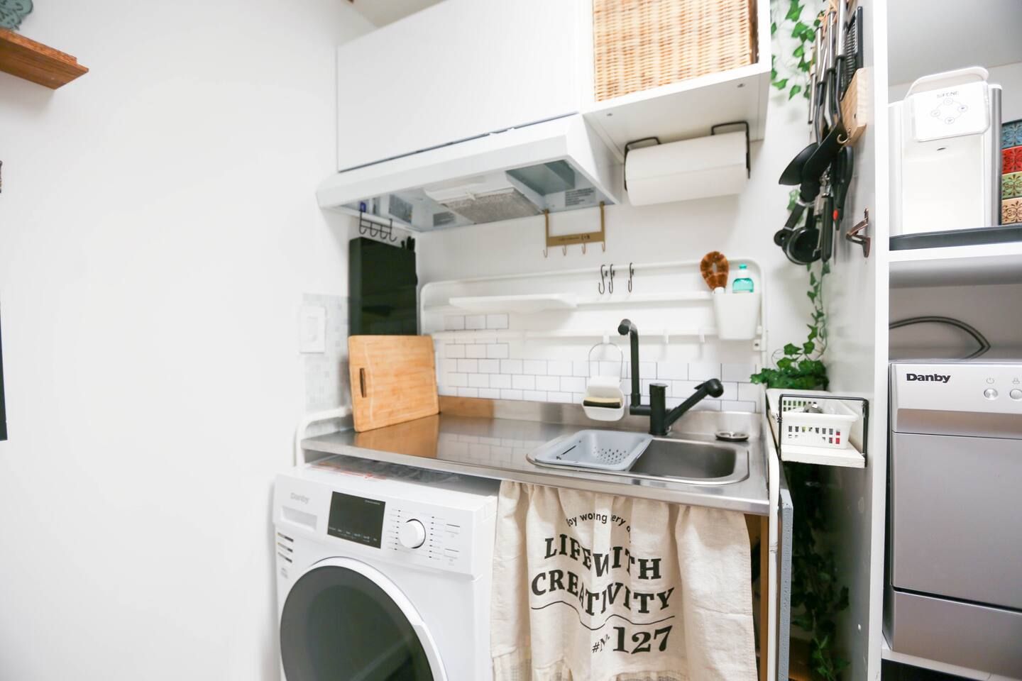 Une cuisine compacte équipée d’un lave-linge, d’un évier et d’un four Danby.