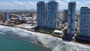 A coastal cityscape with high-rise buildings, a beach, and a clear sky. - Beachfront Luxury | Camino al Mar (Mazatlán)