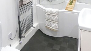 Une salle de bain moderne avec une douche à parois de verre, une baignoire blanche et un porte-serviettes.