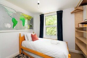 A bedroom with a bed, a map on the wall, a window with curtains, and a wooden shelf. - Comfortable 3BR Townhouse for 6 (London)
