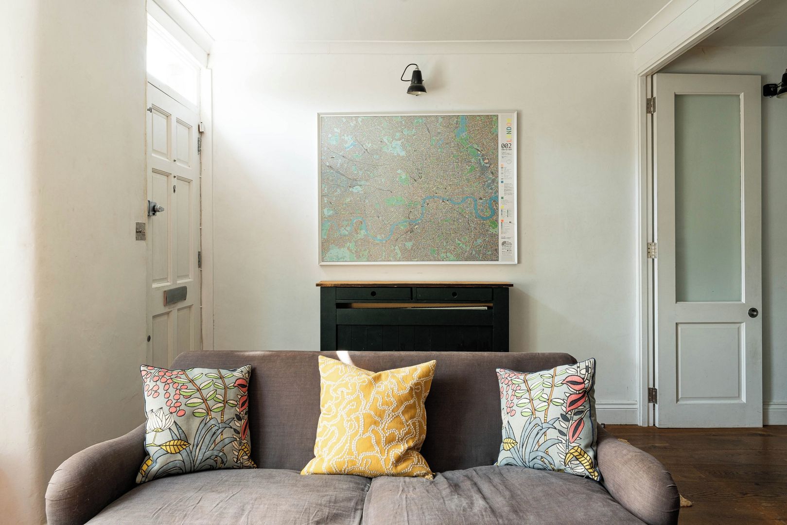 A living room with a sofa, a map on the wall, and a door.