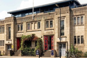 A historic building with 'Public Baths' signage, featuring a central entrance with red doors, a staircase, and a covered upper level. - Comfortable 3BR Townhouse for 6 (London)