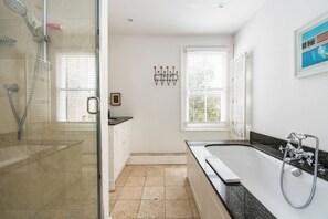 A bathroom with a glass-enclosed shower, a bathtub, and a window with blinds. - Stunning 4 Bedroom Home w/Garden in Fulham (Greater London)