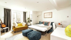 Quarto moderno com cama, sofá, mesinha e um violão.