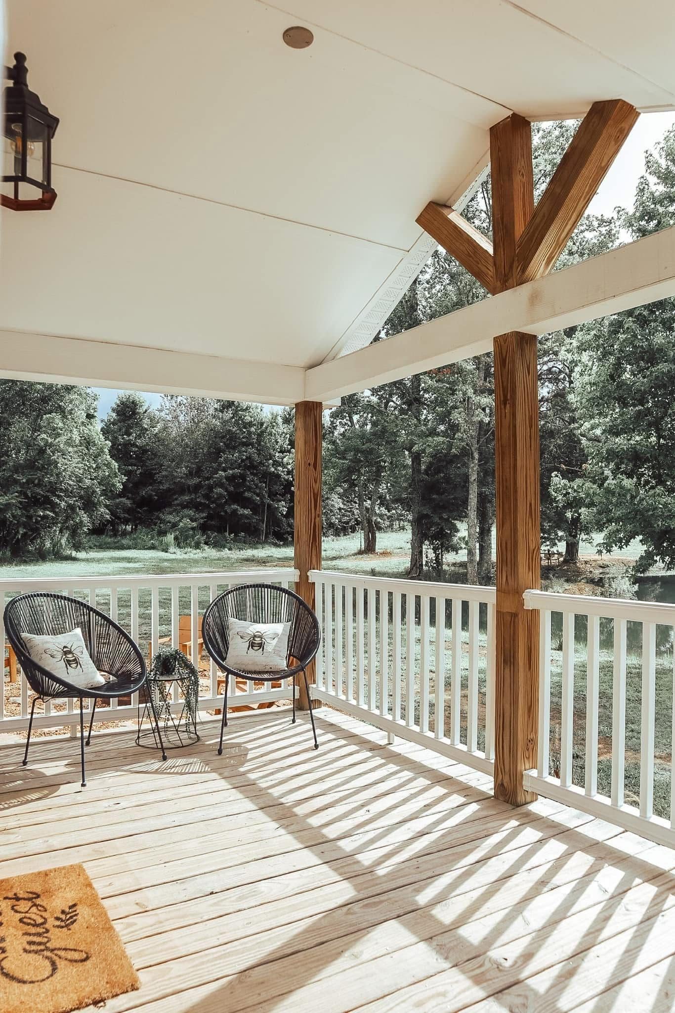 A covered porch with two chairs and a small table, overlooking a natural landscape.