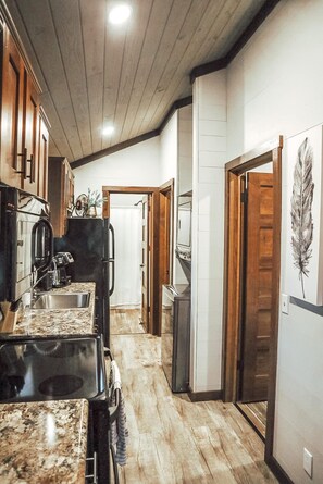 A kitchen with wooden cabinets, a granite countertop, and a refrigerator. - Tiny living, fire pit, pond fishing!!! (Boaz)