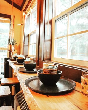 A bar area with wooden tables, black bowls, and a glass of drink. - Tiny living, fire pit, pond fishing!!! (Boaz)