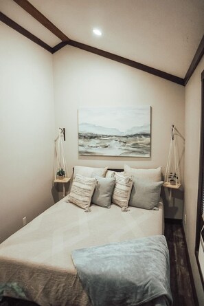Une chambre à coucher avec un lit, un tableau au mur et des lampes de chevet.