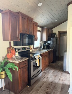Une cuisine avec des meubles de rangement en bois, un four à micro-ondes, une cuisinière et un réfrigérateur.