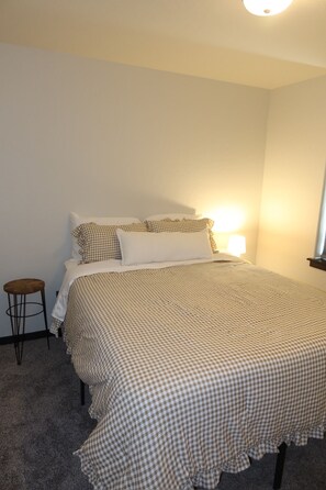 A bedroom with a bed, a nightstand, and a lamp. - Charming 3-bedroom house in serene Athol! 5 Min to Silverwood. Firepit (Athol)
