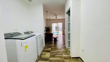 Un pasillo con lavadora, un comedor con mesa y sillas, y vista a una piscina.