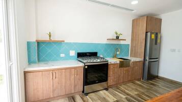 Una cocina con armarios de madera, estufa de acero inoxidable, un lavaplatos y un refrigerador.
