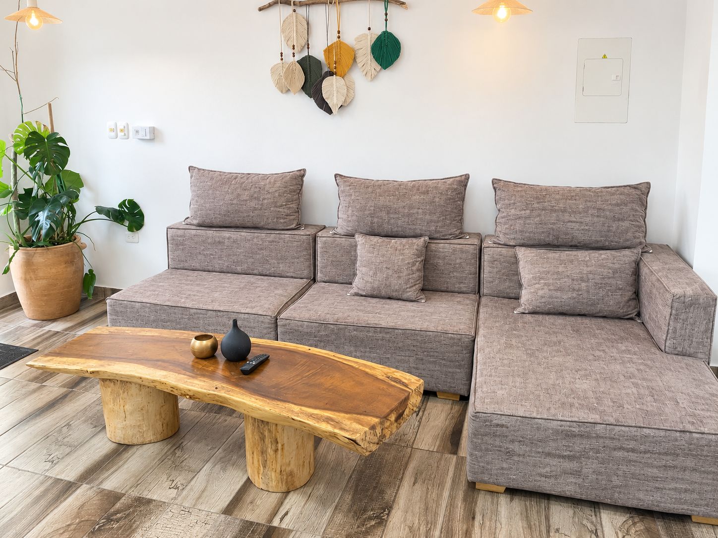 Un salon moderne avec un canapé d’angle, une table basse en bois et une plante en pot.