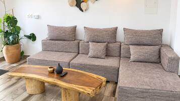 Una sala moderna con un sofá modular, una mesa de centro de madera y una planta en maceta.