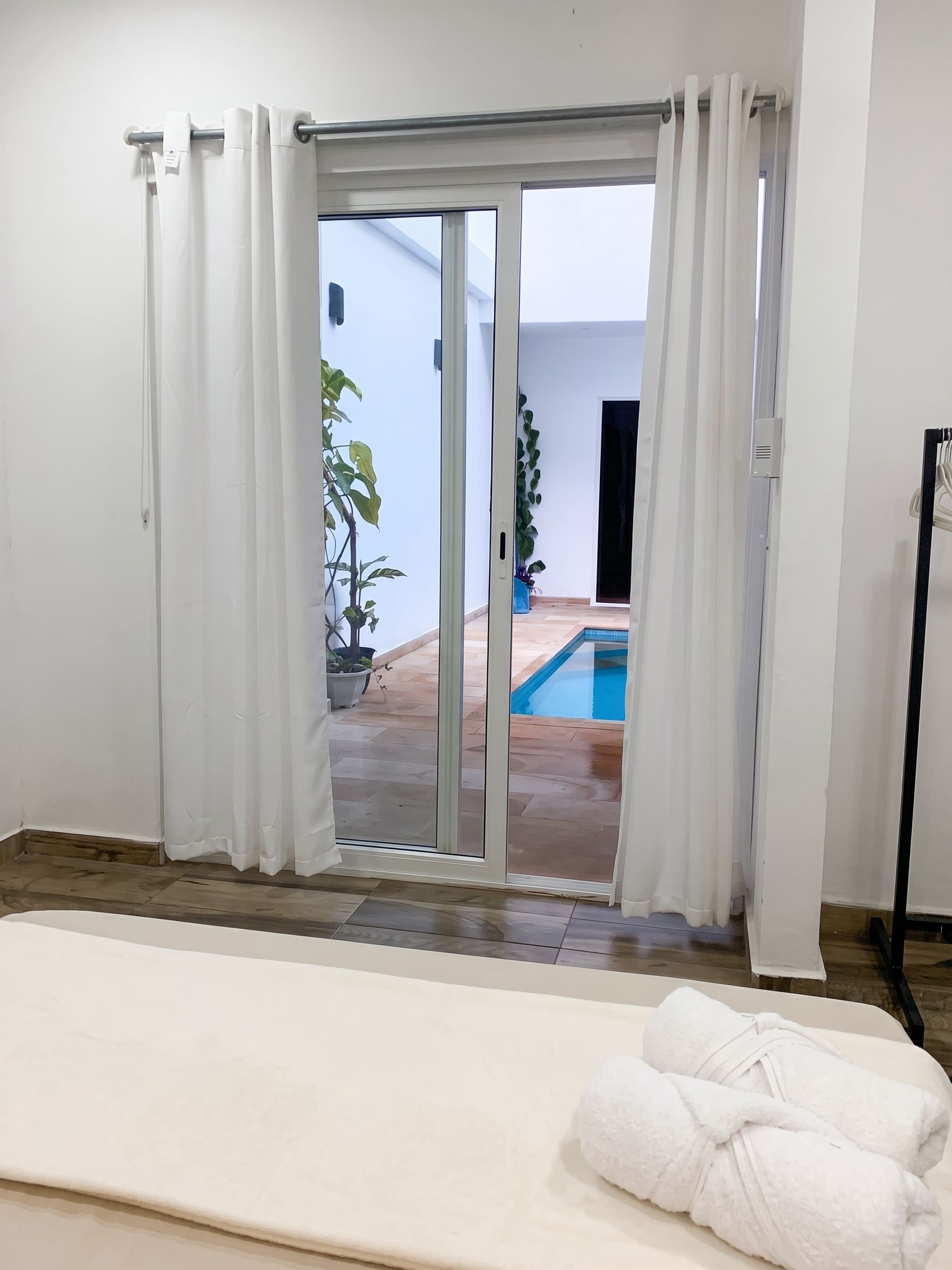 A room with a sliding glass door leading to a pool area, a white bath mat, and a towel on the floor.