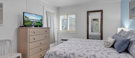 A bedroom with a bed, dresser, television, and a ceiling fan.