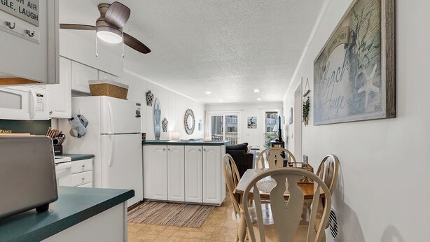 A kitchen with white cabinets, a microwave, and a ceiling fan. - Oceanfront Shore Dr Condo w/ Pools & Beach Access (Myrtle Beach)