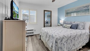 A bedroom with a bed, a ceiling fan, a window, and a wall-mounted TV. - Oceanfront Shore Dr Condo w/ Pools & Beach Access (Myrtle Beach)