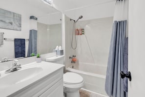 Een moderne badkamer met douche, toilet en wastafel.