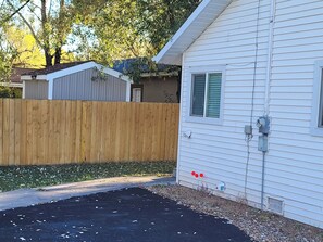 A residential property with a fenced backyard, a driveway, and a house with a visible electrical box.