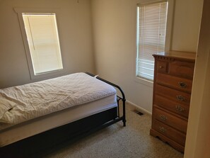 A small, single-bed room with a wooden dresser and two windows with blinds. - White 2-bedroom house in perfect Mountain View location (Mountain View)