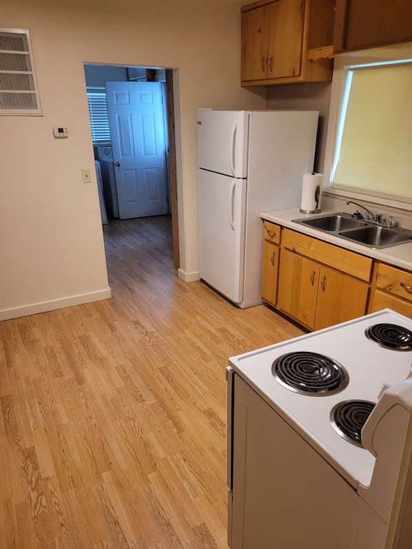 A kitchen with a stove, refrigerator, and wooden cabinets.