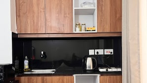 Una cucina compatta con mobili in legno, un piano di lavoro nero e una colonna a giorno.
