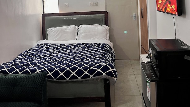 Una camera da letto con un letto, una televisione, una scrivania e una porta.