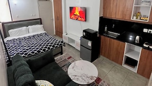 Una camera d'albergo funzionale con un letto, una divisa, un angolo cottura e una TV a parete.