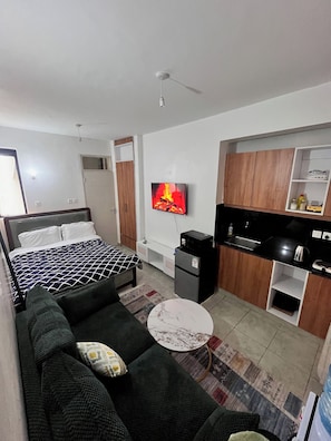 A compact hotel room with a bed, a sofa, a small kitchen area, and a TV mounted on the wall. - Cosy, homely haven made just for you! (Nairobi)