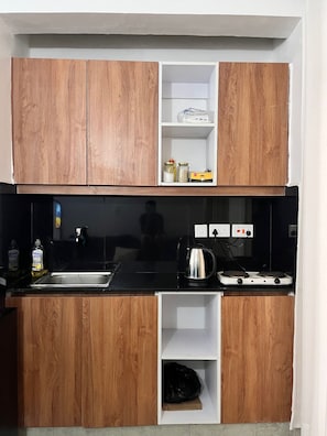 A compact kitchen with wooden cabinets, a black countertop, and a stove. - Cosy, homely haven made just for you! (Nairobi)