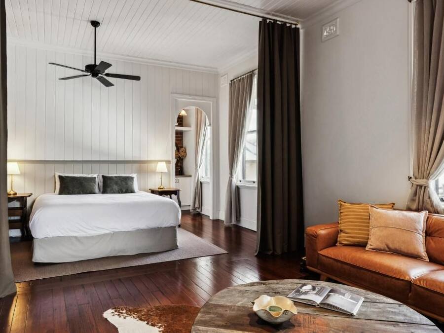 A hotel room with a bed, a leather sofa, a coffee table, and a ceiling fan.