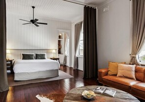 A hotel room with a bed, a leather sofa, a coffee table, and a ceiling fan. - Argyle Hotel Maclean (Maclean)