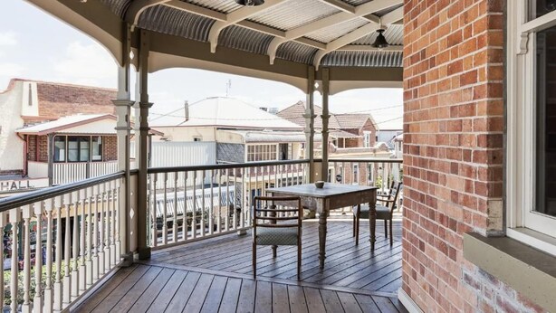 Um espaço coberto ao ar livre com deck de madeira, uma mesa e cadeiras.
