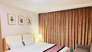 A hotel room with a bed, a chair, a lamp, and three framed pictures on the wall. - One Uptown Residence BGC Stay & Work in BGC | 300Mbps WiFi (Makati City)