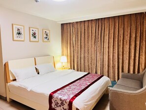 Ein Hotelzimmer mit einem Bett, einem Sessel, einer Lampe und drei gerahmten Bildern an der Wand.