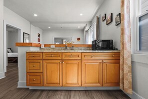 Une cuisine moderne avec des meubles en bois, un plan de travail en granit et un four à micro-ondes encastré.