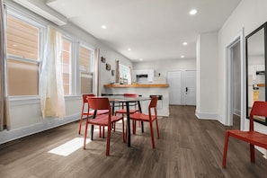 A modern kitchen with white cabinets, a wooden countertop, and a dining area with a table and chairs. - Cozy Detroit House | 3BR Sleeps 6 Near Downtown (Detroit)