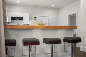 A modern kitchen with white cabinets, a wooden countertop, and a small plant. - Cozy Detroit House | 3BR Sleeps 6 Near Downtown (Detroit)