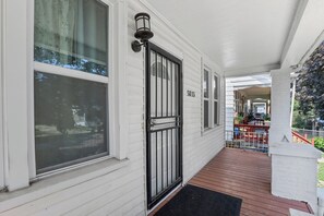 A white house with a black gate, a porch, and a number 5853 on the wall. - Cozy Detroit House | 3BR Sleeps 6 Near Downtown (Detroit)
