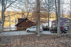 A residential area with a house, parked cars, and a body of water in the background. - Norris Lake Cabin | Dock + Games (Jacksboro)
