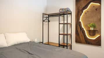 A bedroom with a bunk bed, a bedside table, a wall-mounted shelf with a plant, and a large abstract painting.