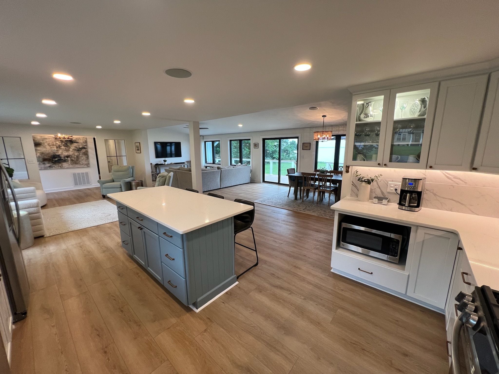 A spacious kitchen with a central island, a dining area with a table and chairs, and a living area with a sofa and television.