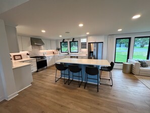 Una cocina moderna con una isla central, taburetes de bar y vistas al exterior.