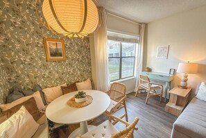 Een gezellige woonkamer met een ronde tafel, een bank en een eethoek.
