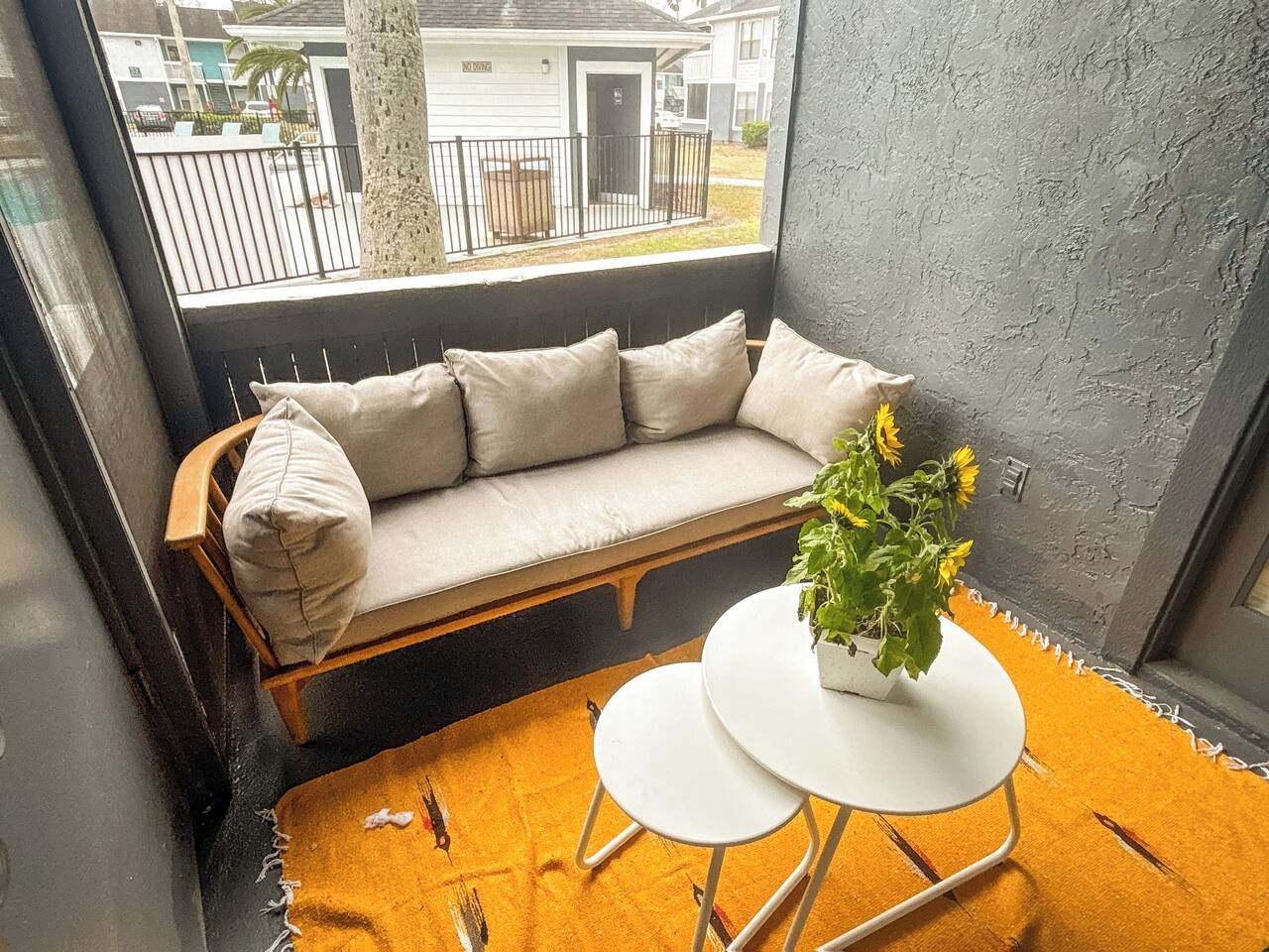 A cozy seating area with a sofa and a small table, a potted plant, and a view through a window.